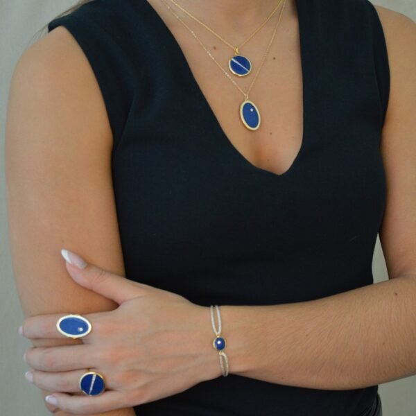 Collier plaquée or avec pendentif rond intérieur en lapis lazuli (bleu) avec un trait esthétique brillant dans son diamètre. Bijou porté, Crédit GEMITY.