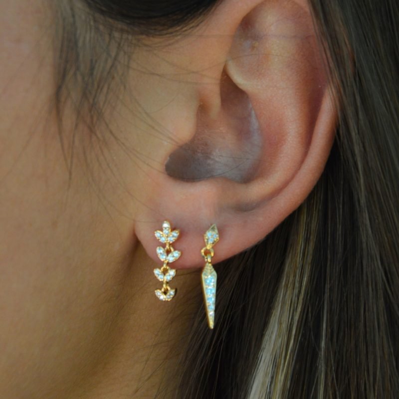 Boucle d'oreille plaquée or pendante. L'accrochet est un losange recouvert de brillants et la partie pendante est un losange alongé vers le bas comportant elle aussi des brillants. Bijou porté, Crédit GEMITY.