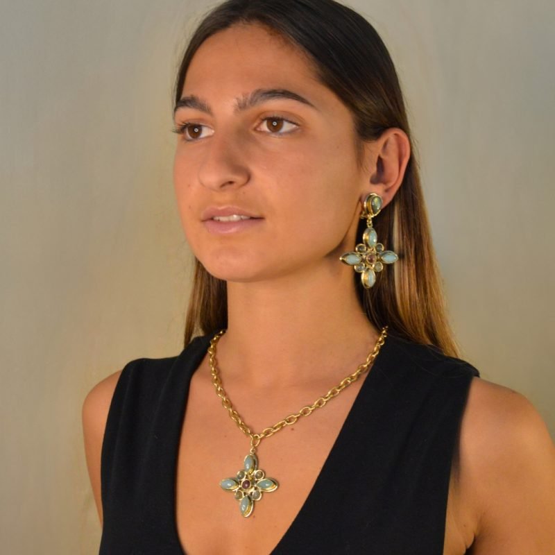Pendentif exquis et boucles, ornés de pétales en amazonite et labradorite. Au cœur de cette composition, une pierre de rhodonite captivante irradie une aura de mystère. Bijoux portés en composition. Crédit GEMITY.
