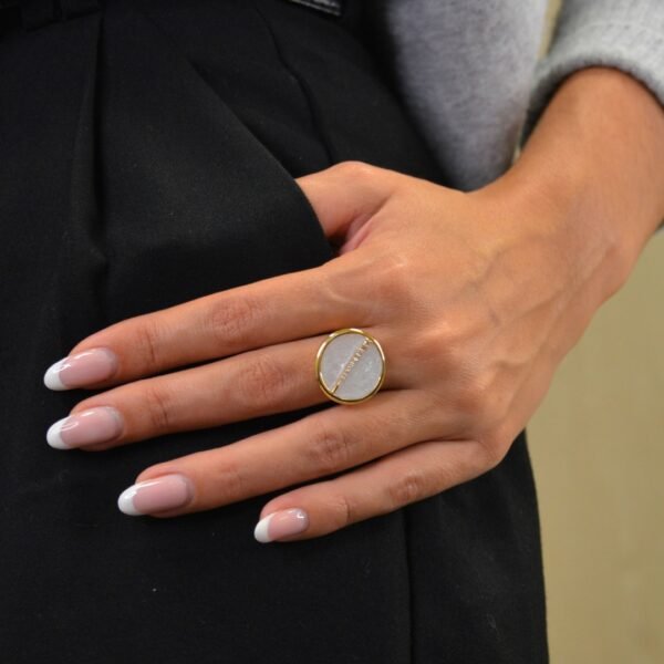 Bague plaquée or ronde intérieur en nacre (blanc) avec un trait esthétique brillant dans son diamètre. Bijou porté, Crédit GEMITY.