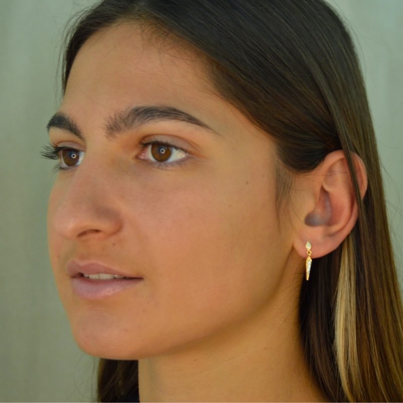 Boucle d'oreille plaquée or pendante. L'accrochet est un losange recouvert de brillants et la partie pendante est un losange alongé vers le bas comportant elle aussi des brillants. Bijou porté, Crédit GEMITY.