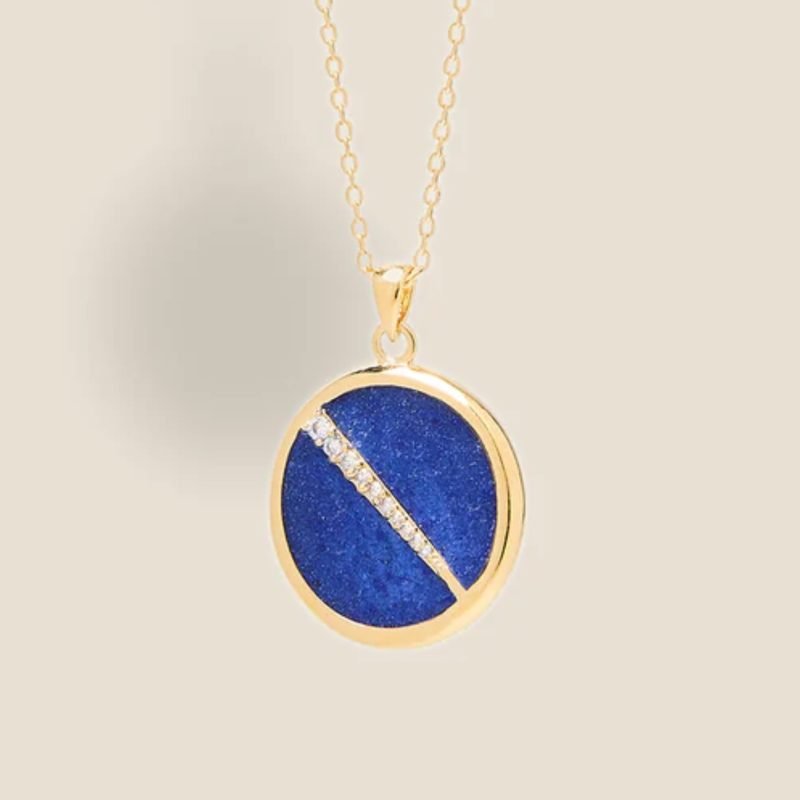 Collier plaquée or avec pendentif rond intérieur en lapis lazuli (bleu) avec un trait esthétique brillant dans son diamètre. Bijou seul, Crédit Léo Sédim
