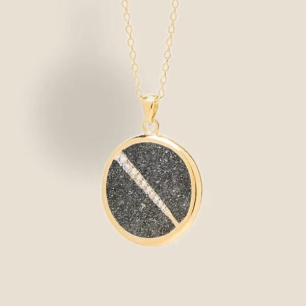 Collier plaquée or avec pendentif rond intérieur en pyrite (noire) avec un trait esthétique brillant dans son diamètre. Bijou seul, Crédit Léo Sédim