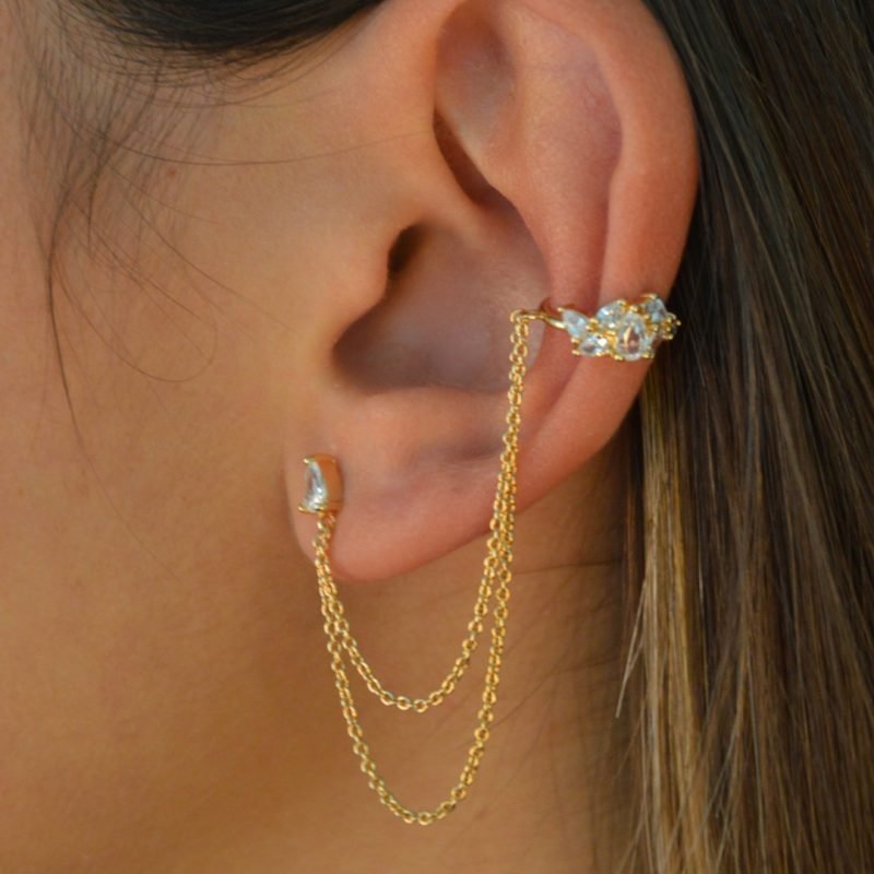 Mono-boucle d'oreille plaquée or composée de deux accroches (2 trous) en petits brillants de zirconium (triangle et composition de plusieurs brillants)reliées par deux chainettes. Bijou porté, Crédit GEMITY.