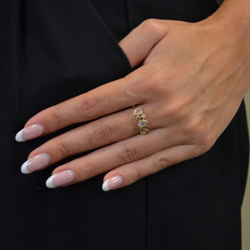 Notre bague Ondine en plaqué or est un bijou qui allie glamour et raffinement, ornée d'une succession de pierres semi-précieuses en quartz rose, améthyste, labradorite et zircon.. Bijou porté, Crédit GEMITY.