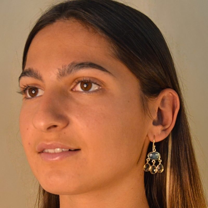 Adèle sont de superbes boucles d'oreilles en plaqué or 3 microns pendantes ornées de citrine étincelante et de trois kyanites vertes. Bijou porté, Crédit GEMITY.