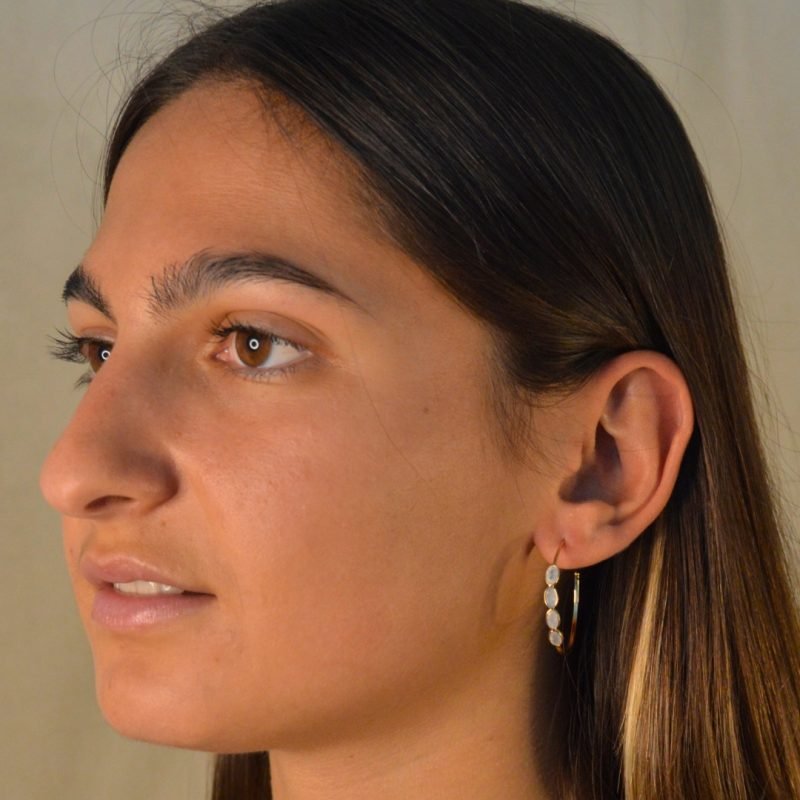 Magnifiques boucles d'oreilles créoles. Les petits ovales disposés sur les créoles sont des pierres de lune qui portent une beauté mystérieuse et envoûtent les sens.. Bijou porté, Crédit GEMITY.