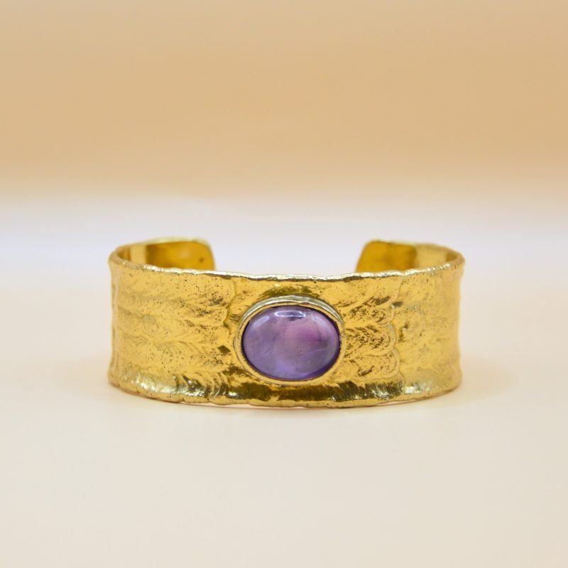 Bracelet jonc ajustable inspiré des mystères du désert. Son design et sa texture lisse rappelle les subtiles nuances du sable doré qui s'étend à perte de vue, tandis que sa pierre centrale en améthyste ajoute une touche d'élégance et de fraîcheur. . Bijou seul, Crédit GEMITY