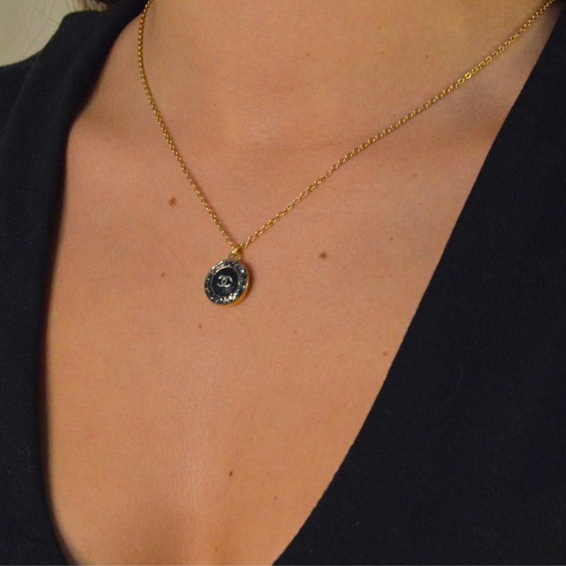 Upcycling d’un bouton noir à strass d’une maison de luxe monté en pendentif sur une chaîne de mailles fines (2 mm) d’une longueur de 50 cm. Bijou seul, Crédit GEMITY. Upcycling d’un bouton noir à strass d’une maison de luxe monté en pendentif sur une chaîne de mailles fines (2 mm) d’une longueur de 50 cm. Bijou porté, Crédit GEMITY.