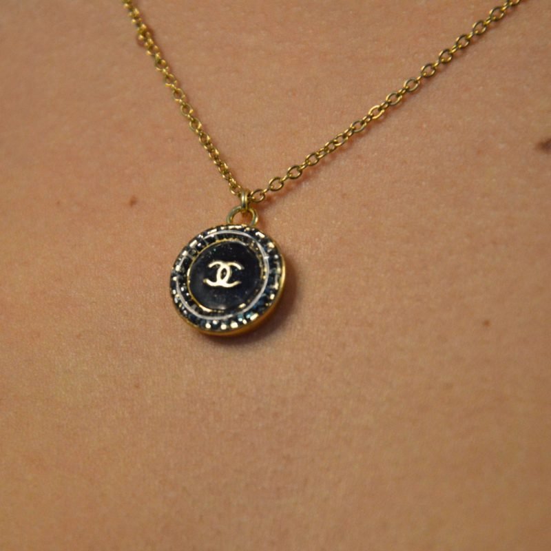 Upcycling d’un bouton noir à strass d’une maison de luxe monté en pendentif sur une chaîne de mailles fines (2 mm) d’une longueur de 50 cm. Bijou seul, Crédit GEMITY. Upcycling d’un bouton noir à strass d’une maison de luxe monté en pendentif sur une chaîne de mailles fines (2 mm) d’une longueur de 50 cm. Bijou porté, Crédit GEMITY.