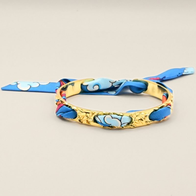 Le bracelet FÉERIE est un des intemporels les plus appréciés de la marque, pour celles qui recherchent le raffinement et la discrétion. C'est le bracelet le plus fin de nos créations (0,8 cm de largeur), travaillé de petites lianes et feuilles, il est à la fois très élégant et poétique. Ce bracelet est accompagné du ruban perfect match neutre. Bijou seul, Crédit GEMITY