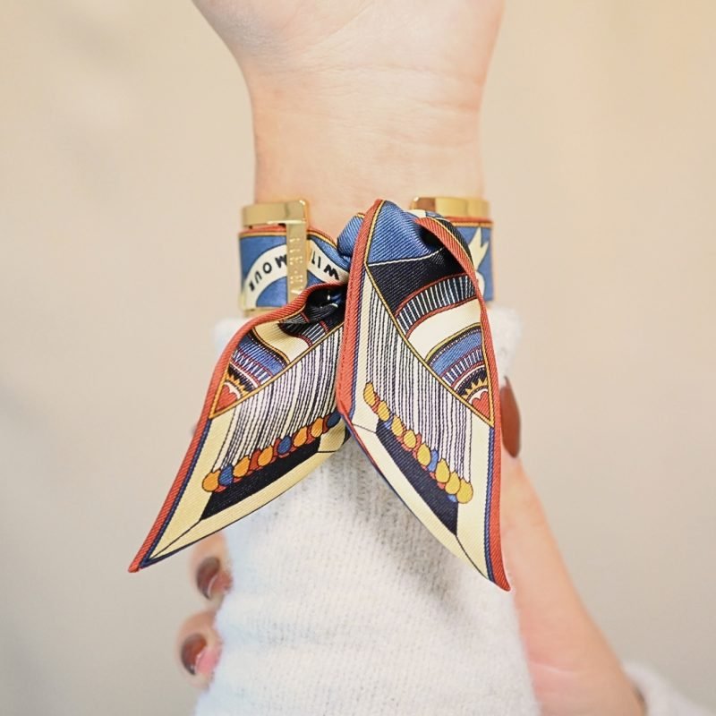 Manchette dorée ajourée. Se porte avec un foulard ou non. Sur la photo, la manchette est accompagnée du ruban perfect match neutre. Bijou porté, Crédit GEMITY.