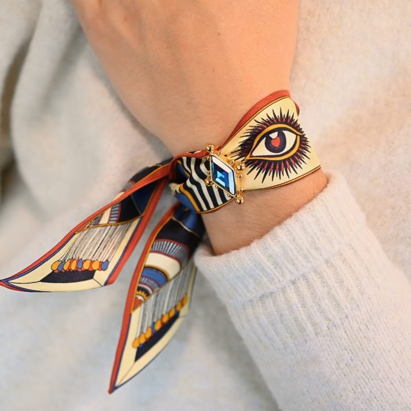 Voici notre nouvel ornement dédié à nos rubans en soie de 4 cm. Une vraie beauté inspirée de l'univers du Cirque, incrustée d'un strass facetté tie & dye rose (bicolore). Cet ornement est porté avec le ruban carrousel neutre. Bijou porté, Crédit GEMITY.