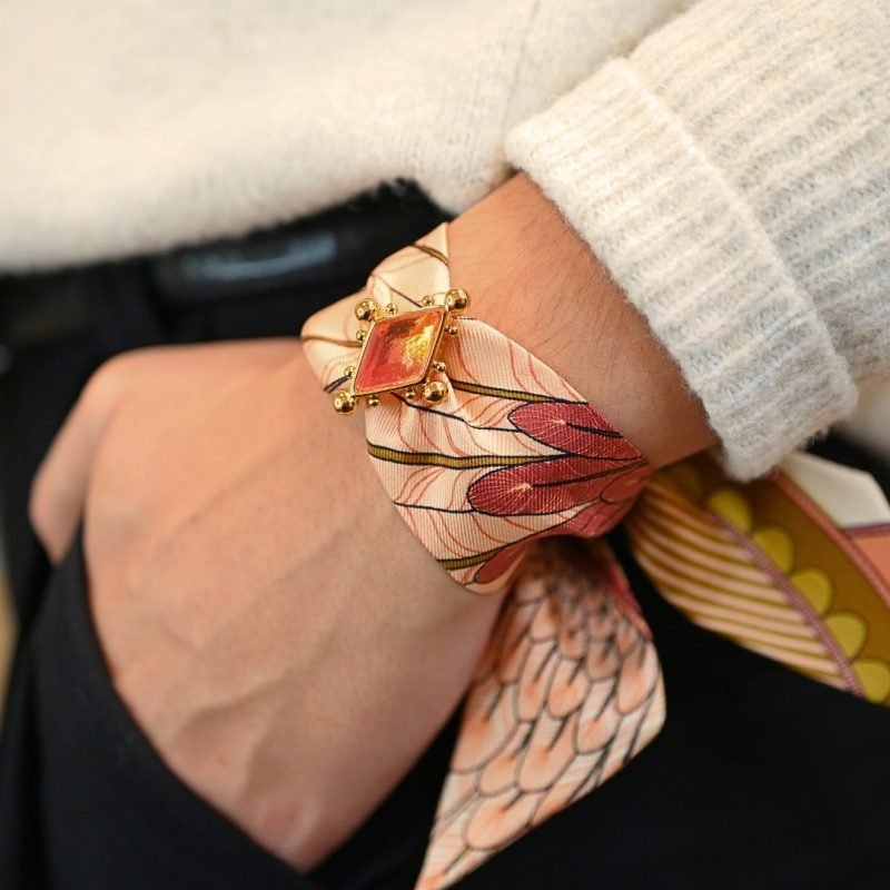 Voici notre nouvel ornement dédié à nos rubans en soie de 4 cm. Une vraie beauté inspirée de l'univers du Cirque, incrustée d'un strass facetté tie & dye rose (bicolore). Cet ornement est porté avec le ruban carrousel neutre. Bijou porté, Crédit GEMITY
