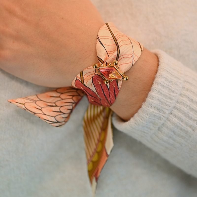 Voici notre nouvel ornement dédié à nos rubans en soie de 4 cm. Une vraie beauté inspirée de l'univers du Cirque, incrustée d'un strass facetté tie & dye rose (bicolore). Cet ornement est porté avec le ruban carrousel neutre. Bijou porté, Crédit GEMITY