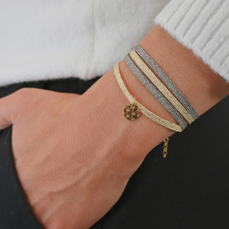 "Bracelet double tours en tissu de deux coloris différents avec une pastille martelée dorée à l’or fin. Fermoir en plaqué or réglable . Bijou porté, Crédit GEMITY."