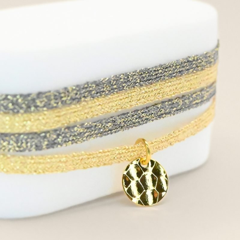 "Bracelet double tours en tissu de deux coloris différents avec une pastille martelée dorée à l’or fin. Fermoir en plaqué or réglable . Bijou seul, Crédit GEMITY"