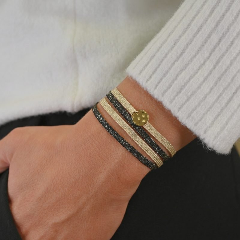 "Bracelet double tours en tissu de deux coloris différents avec une pastille martelée dorée à l’or fin. Fermoir en plaqué or réglable . Bijou porté, Crédit GEMITY."