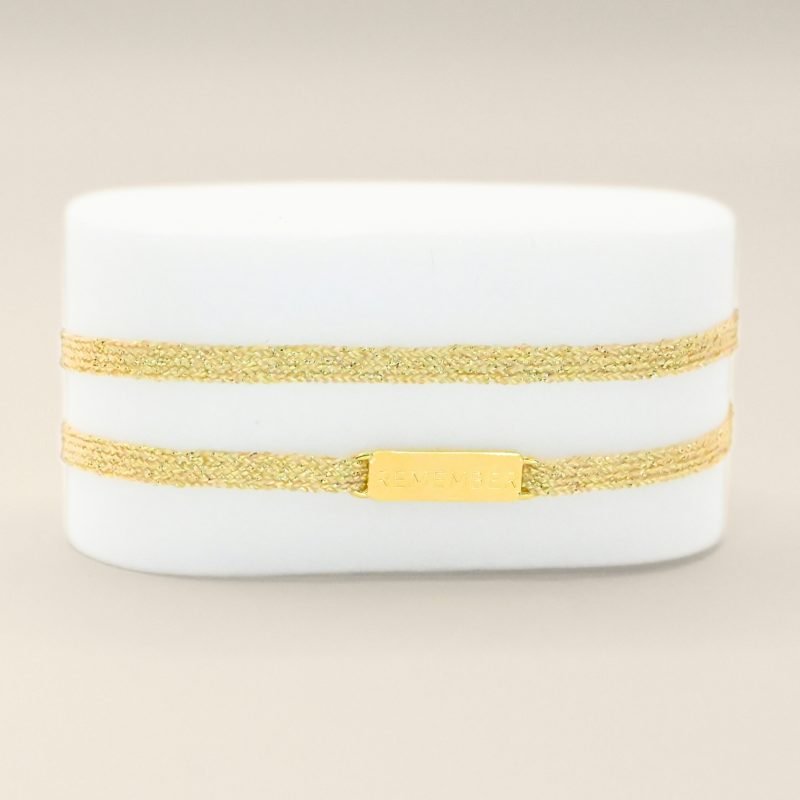 "Bracelet double tours en tissu avec une plaque REMEMBER en plaqué or (3 microns) fait main. Fermoir en plaqué or réglable . Bijou seul, Crédit GEMITY"