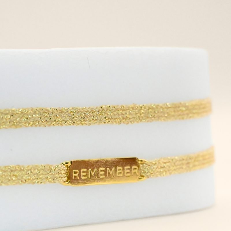 "Bracelet double tours en tissu avec une plaque REMEMBER en plaqué or (3 microns) fait main. Fermoir en plaqué or réglable . Bijou seul, Crédit GEMITY"