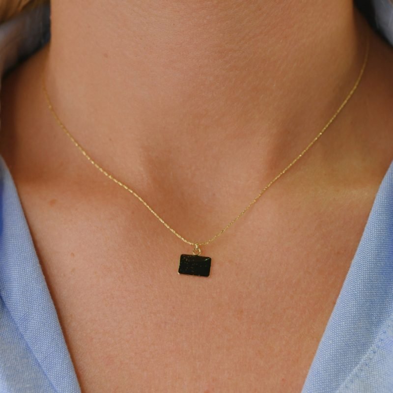 Collier plaqué or avec plaque extra-fine réversible, inscription LOVE d'un côté et émail noir pailleté de l'autre côté. Bijou porté, Crédit GEMITY.