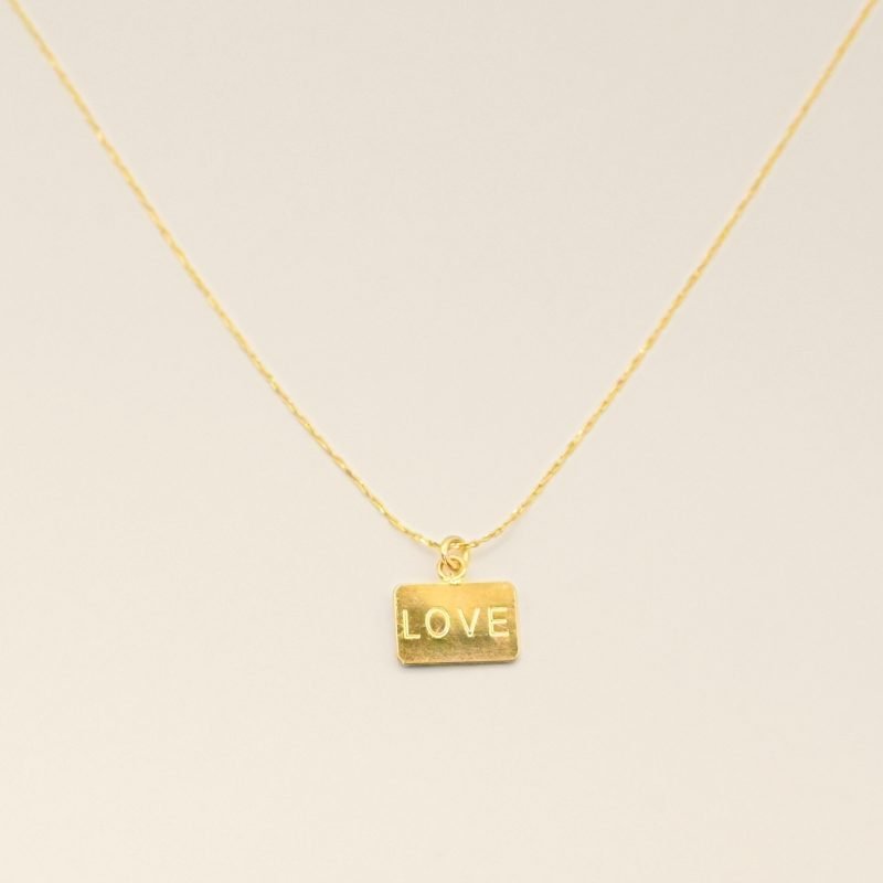 Collier plaqué or avec plaque extra-fine réversible, inscription LOVE d'un côté et émail noir pailleté de l'autre côté. Bijou seul, Crédit GEMITY