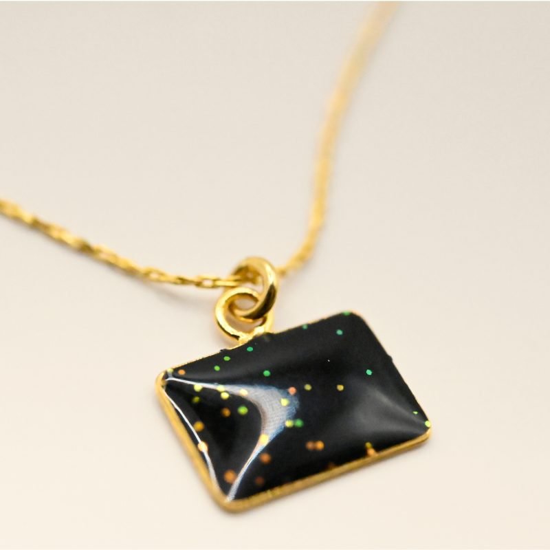 Collier plaqué or avec plaque extra-fine réversible, inscription LOVE d'un côté et émail noir pailleté de l'autre côté. Bijou seul, Crédit GEMITY