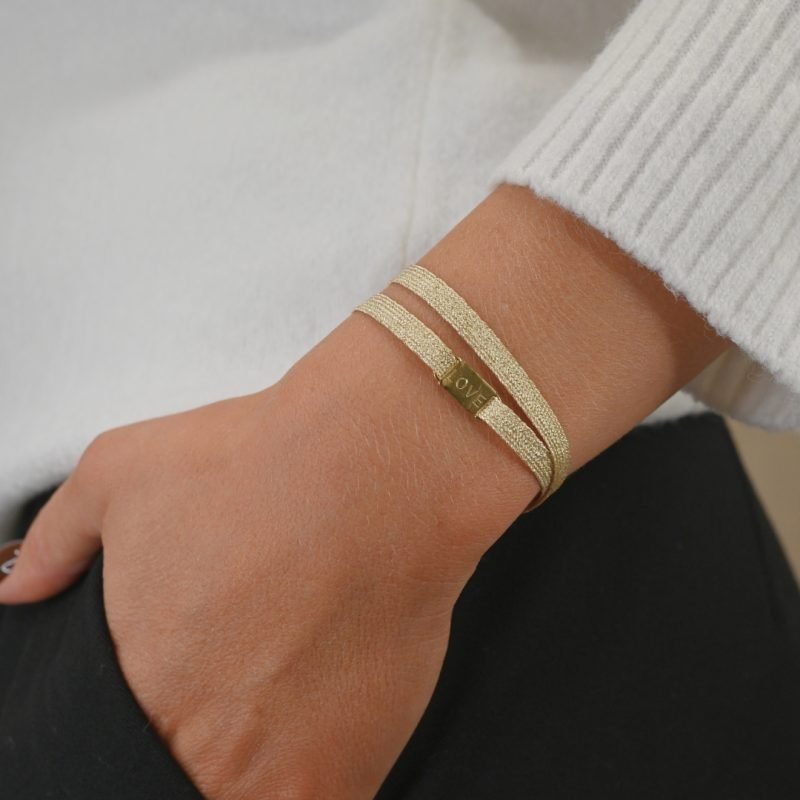 "Bracelet double tours avec une plaque LOVE en plaqué or (3 microns) fait main. Fermoir en plaqué or réglable . Bijou porté, Crédit GEMITY."