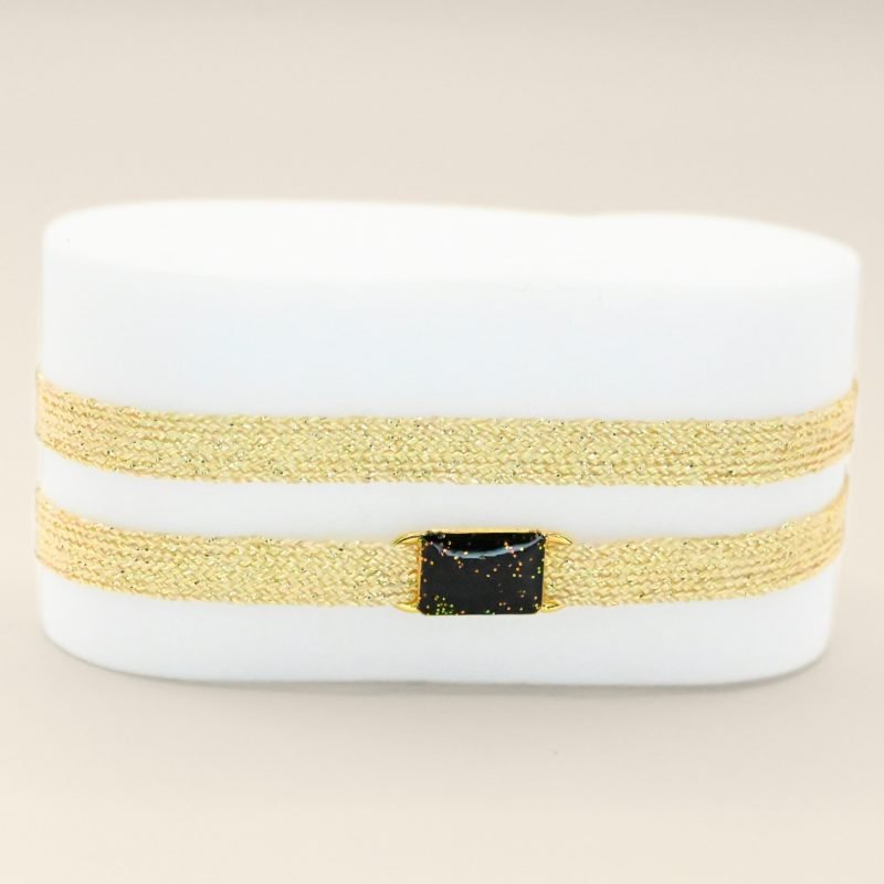 "Bracelet double tours en tissu avec une plaque noire pailleté en plaqué or (3 microns) fait main. Fermoir en plaqué or réglable . Bijou seul, Crédit GEMITY"