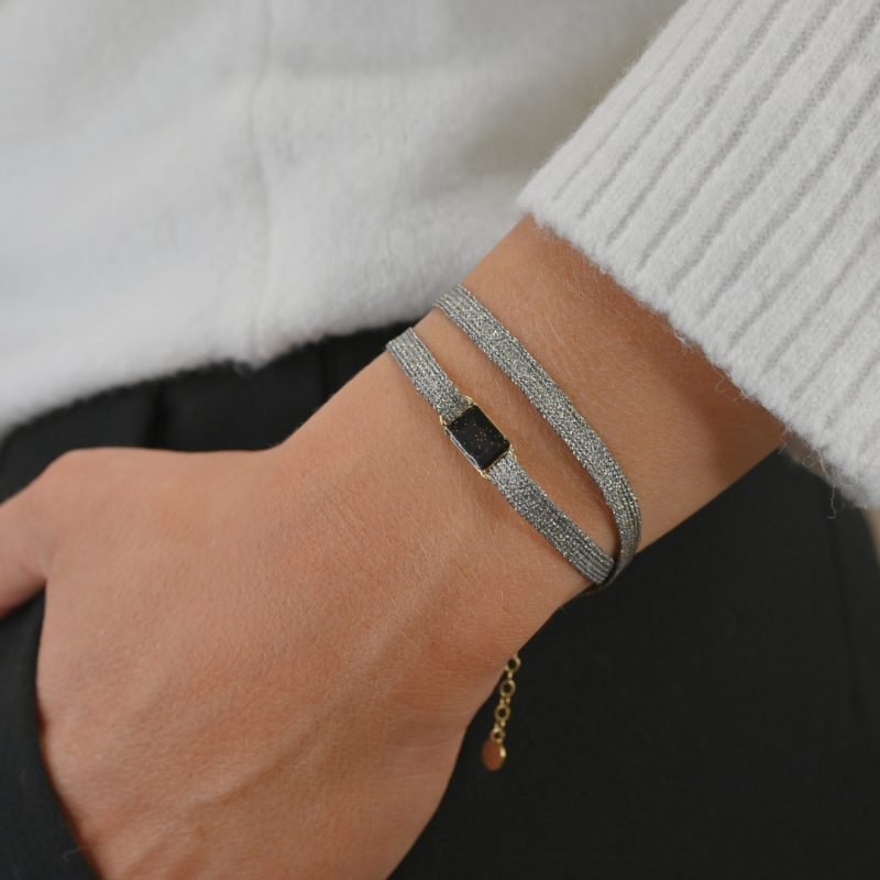 "Bracelet double tours en tissu avec une plaque noire pailleté en plaqué or (3 microns) fait main. Fermoir en plaqué or réglable . Bijou porté, Crédit GEMITY."