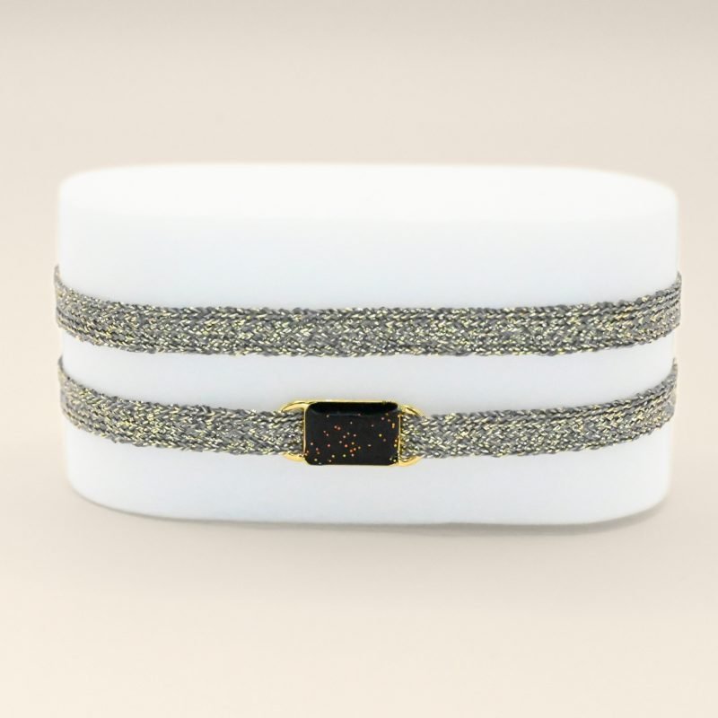 "Bracelet double tours en tissu avec une plaque noire pailleté en plaqué or (3 microns) fait main. Fermoir en plaqué or réglable . Bijou porté, Crédit GEMITY."