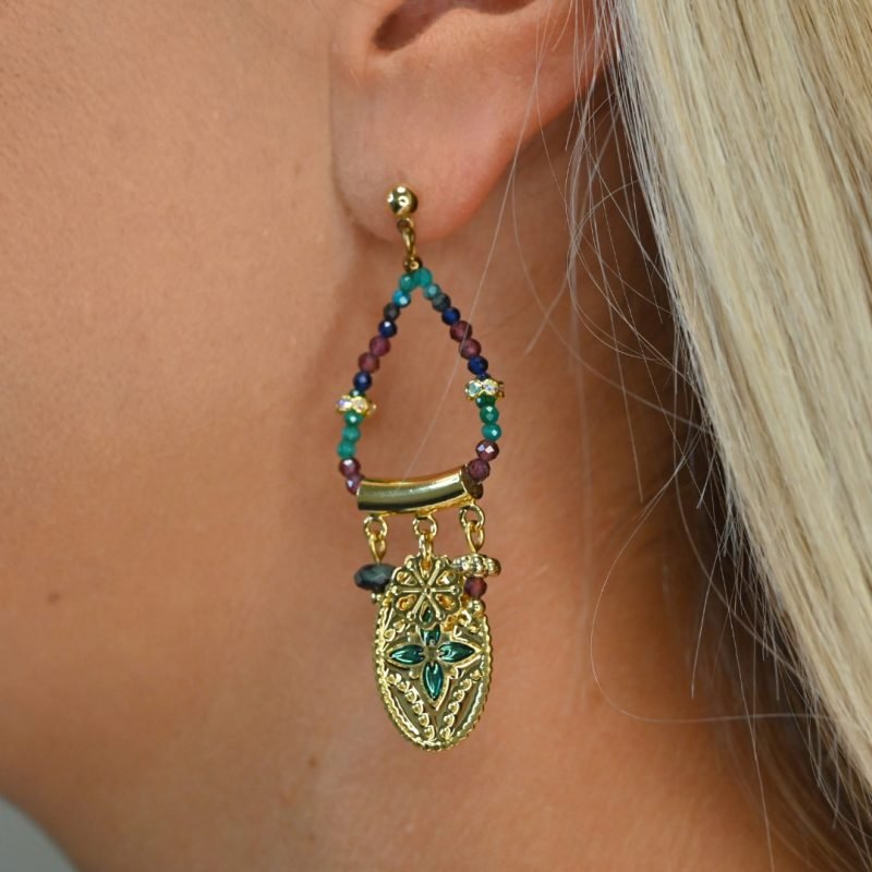 Ces boucles d’oreilles sont un véritable hommage à l’art indien. Chaque pièce est façonnée et émaillée à la main, mettant en valeur le savoir-faire traditionnel. Les pendentifs ovales évoquent des éléments floraux tels que le lotus, symbole porte-bonheur. Bijou porté, Crédit GEMITY.
