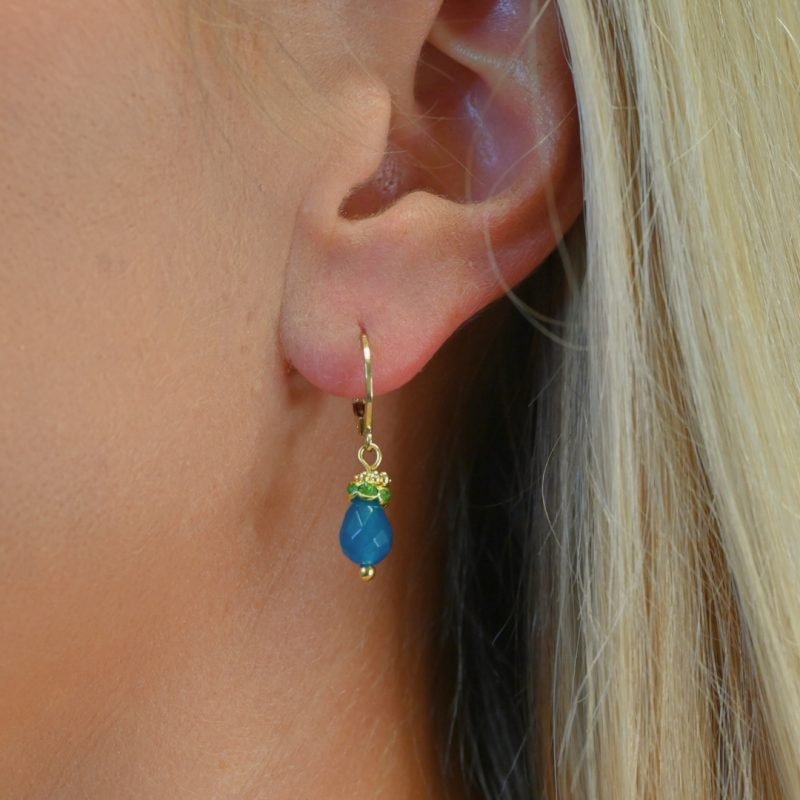 Petites boucles d'oreille parfaites pour le quotidien ou pour être portées en association avec le collier Jaipur par exemple. Elles sont très légères et d'une couleur éclatante. Un anneau strassé vient faire le pont entre la goutte et un petit anneau doré orné de mini boules typiquement indien. Bijou porté, Crédit GEMITY.