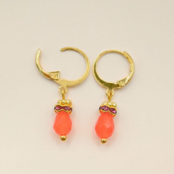 Petites boucles d'oreille parfaites pour le quotidien ou pour être portées en association avec le collier Jaipur par exemple. Elles sont très légères et d'une couleur éclatante. Un anneau strassé vient faire le pont entre la goutte et un petit anneau doré orné de mini boules typiquement indien. Bijou seul, Crédit GEMITY