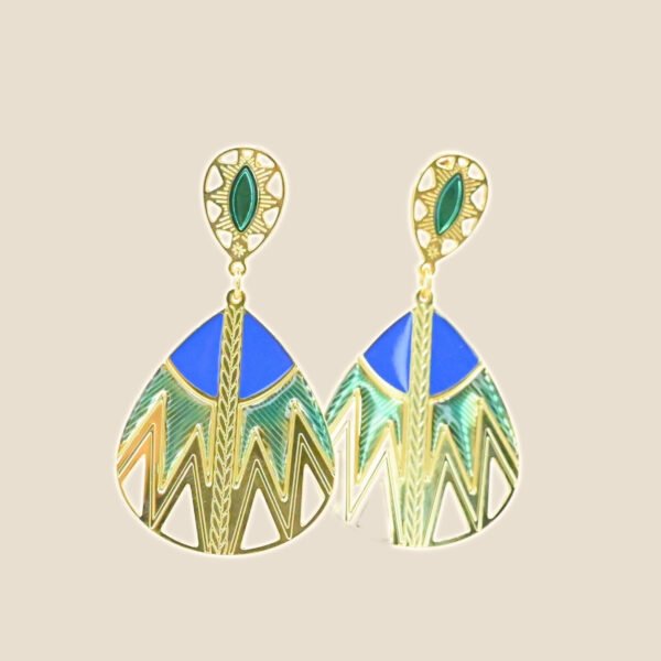 Inspirée des paniers du Sahara, cette paire de boucles d'oreille TANI est très originale par sa combinaison de couleurs et de motifs géométriques. Une tresse gravée fait le lien entre la puce qui habille finement le lobe de l'oreille et la boucle pendante. Bijou seul, Crédit GEMITY