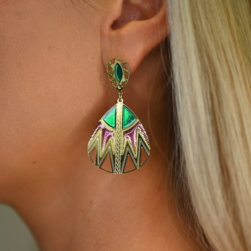 Inspirée des paniers du Sahara, cette paire de boucles d'oreille TANI est très originale par sa combinaison de couleurs et de motifs géométriques. Une tresse gravée fait le lien entre la puce qui habille finement le lobe de l'oreille et la boucle pendante. Bijou porté, Crédit GEMITY.