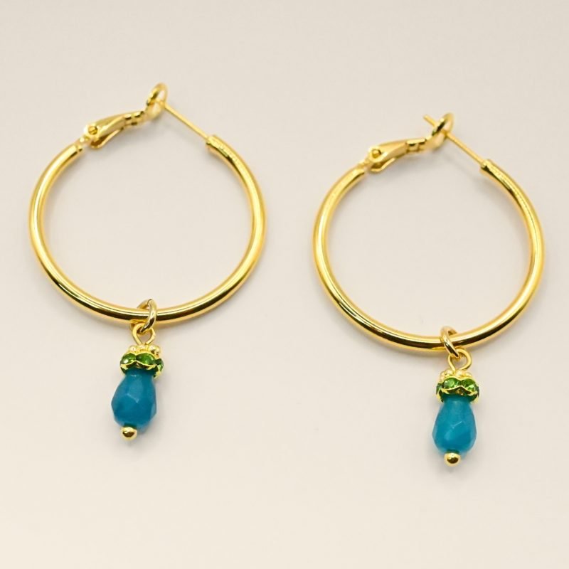 Découvrez l’élégance intemporelle de cette créole doré à l’or fin, ornée d’un délicat pendentif en pierre de jade teinté. Ces boucles d’oreilles allient sophistication et modernité, parfaites pour sublimer toutes vos tenues, qu’elles soient décontractées ou habillées. Bijou seul, Crédit GEMITY