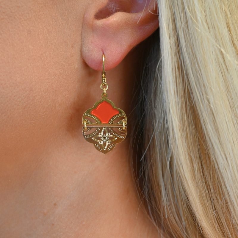 Comme un hommage aux volutes de l'architecture et palais indiens, ces boucles d’oreilles tout en courbes sublimeront votre visage. Elles sont émaillées de résine colorée transparente qui donne de la profondeur à la boucle. Elles sont en 2 parties pour plus de fluidité et de légèreté. La partie inférieure est gravée d'une fleur à 4 pétales. D'un style bohème chic, ce joli modèle vous accompagnera partout. Bijou porté, Crédit GEMITY.