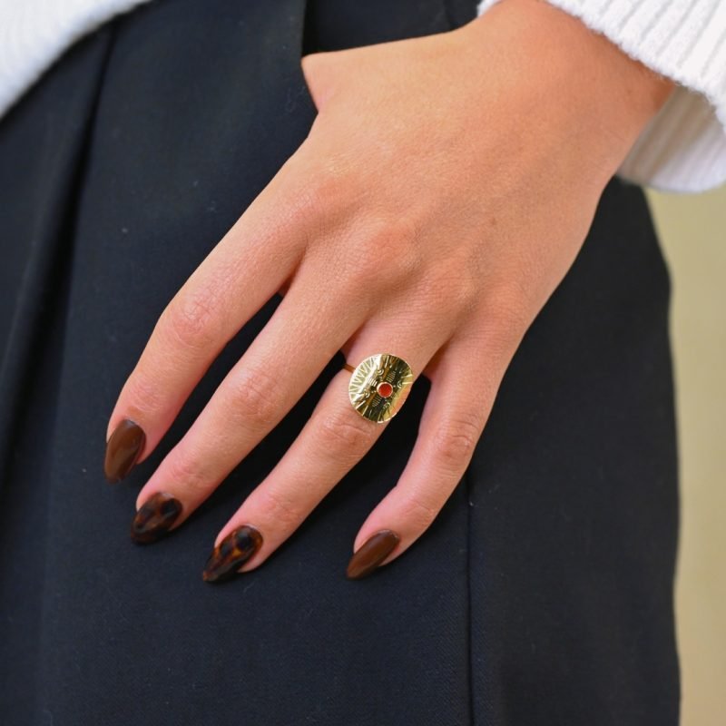 Cette jolie bague habille votre doigt avec son motif rond et courbé. Elle est gravée de motifs et surmonté d'un cabochon de couleur, émaillé à la main. Bijou porté, Crédit GEMITY.
