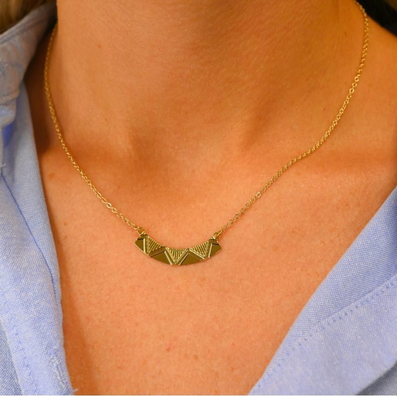 Voici un collier graphique avec des motifs finement gravés à la façon d’un zig zag, facile à porter et à associer. Bijou porté, Crédit GEMITY.