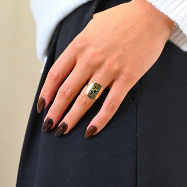 Cette jolie bague habille votre doigt avec son motif rond et courbé. Elle est gravée de motifs et surmonté d'un cabochon de couleur, émaillé à la main. Bijou porté, Crédit GEMITY.