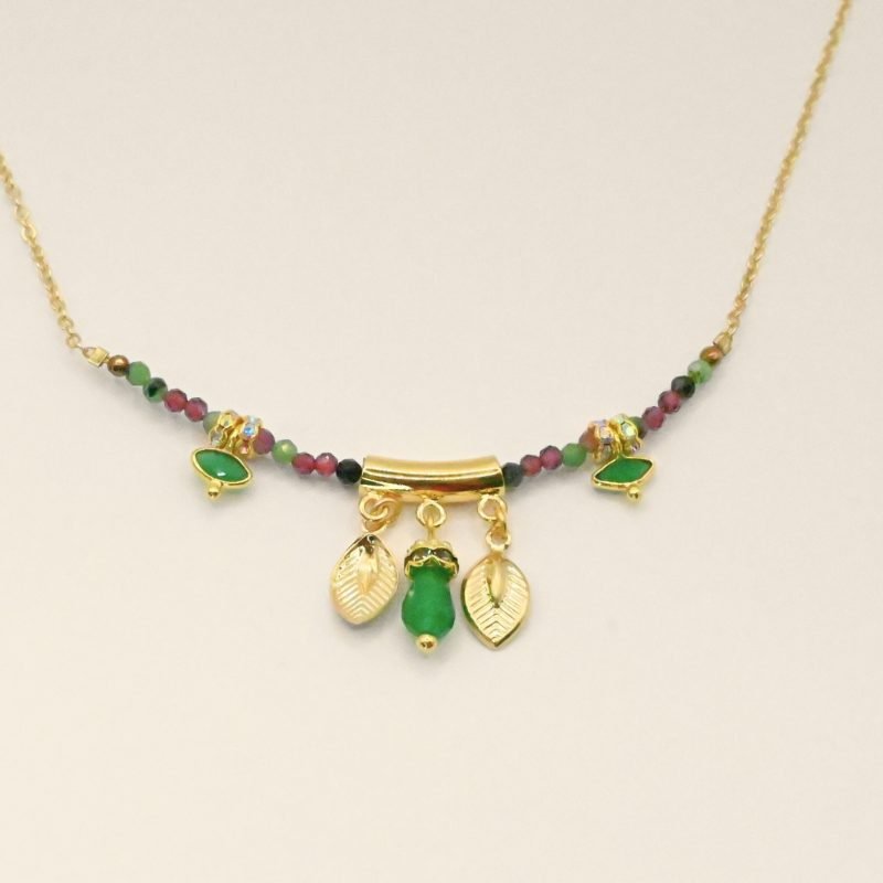 "Les pampilles feuilles rappellent l'univers luxuriant des motifs indiens, les rondelles de strass soulignent les pierres serties et les fines perles donnent du cachet à ce collier bohème! laiton doré à l’or fin 24 carats, cordon polyester et coton. Pierres serties (agate verte et tourmaline rose), jade teinté, perles en pierre semi-précieuses, strass . Bijou seul, Crédit GEMITY"