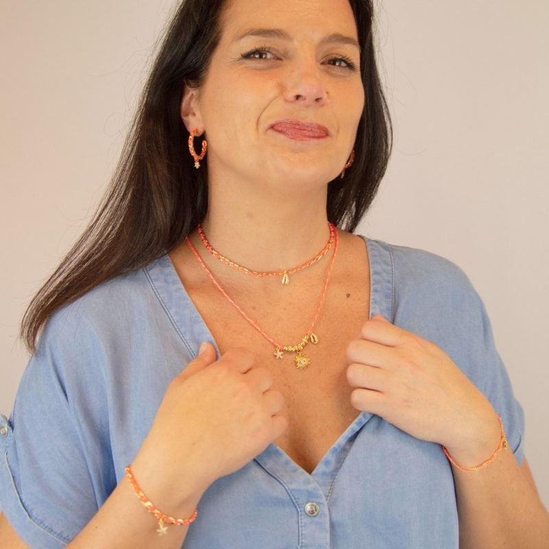 "Les boucles d'oreilles Monsens, inspirées de la collection Couture, où l'on retrouve un célèbre charm et une couleur dominante dans la maille. Taille : 27 mm de diamètre Composition : plaqué or et fil de coton.. Bijou porté, Crédit GEMITY."