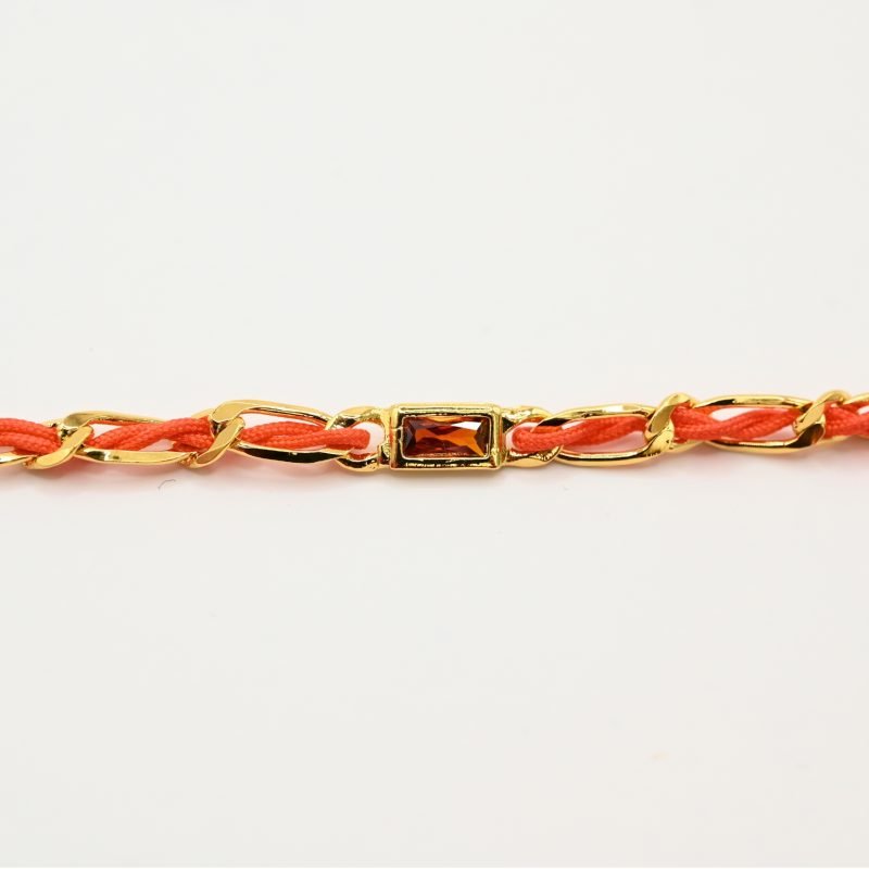 "Bracelet avec un cordon doré et un gemme transparent en son centre. Composition : 100% plaqué or. Contient 1 strass coloré transparent. . Bijou seul, Crédit GEMITY"