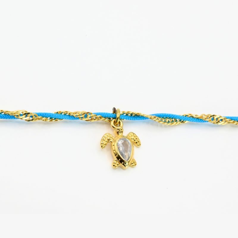 "Byzance, c'est l'idée d'avoir un bijou d'inspiration vintage de nos grands-mères, tout en étant moderne avec des charms fun, colorés, et porte-bonheur. Composition : acier inoxydable, charms en plaqué or et tissu en coton polyester. Fermoir réglable. Utilisation possible sous la douche.. Bijou seul, Crédit GEMITY"