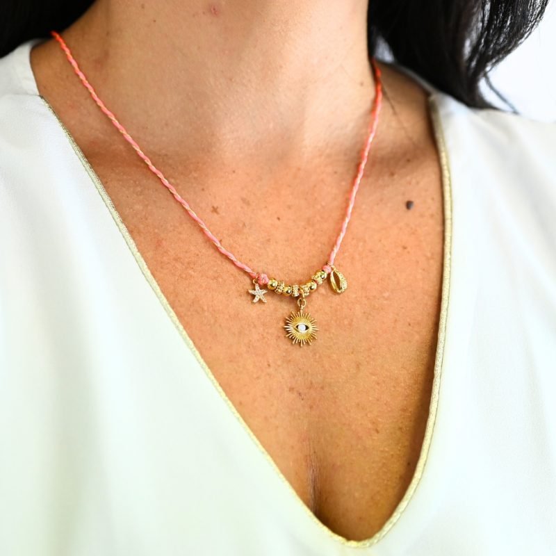 "Ces colliers mêlent fils de coton torsadé, touches dorées et couleurs vibrantes, pour une alliance parfaite entre raffinement et fraîcheur de l’océan. Ornés de trois charms et de détails en plaqué or, ils rappellent l’énergie chic des vagues et le charme intemporel des rivages de Biarritz. Une harmonie bohème et sophistiquée à porter au quotidien. Composition : Plaqué or et fils de coton torsadés. . Bijou porté, Crédit GEMITY."