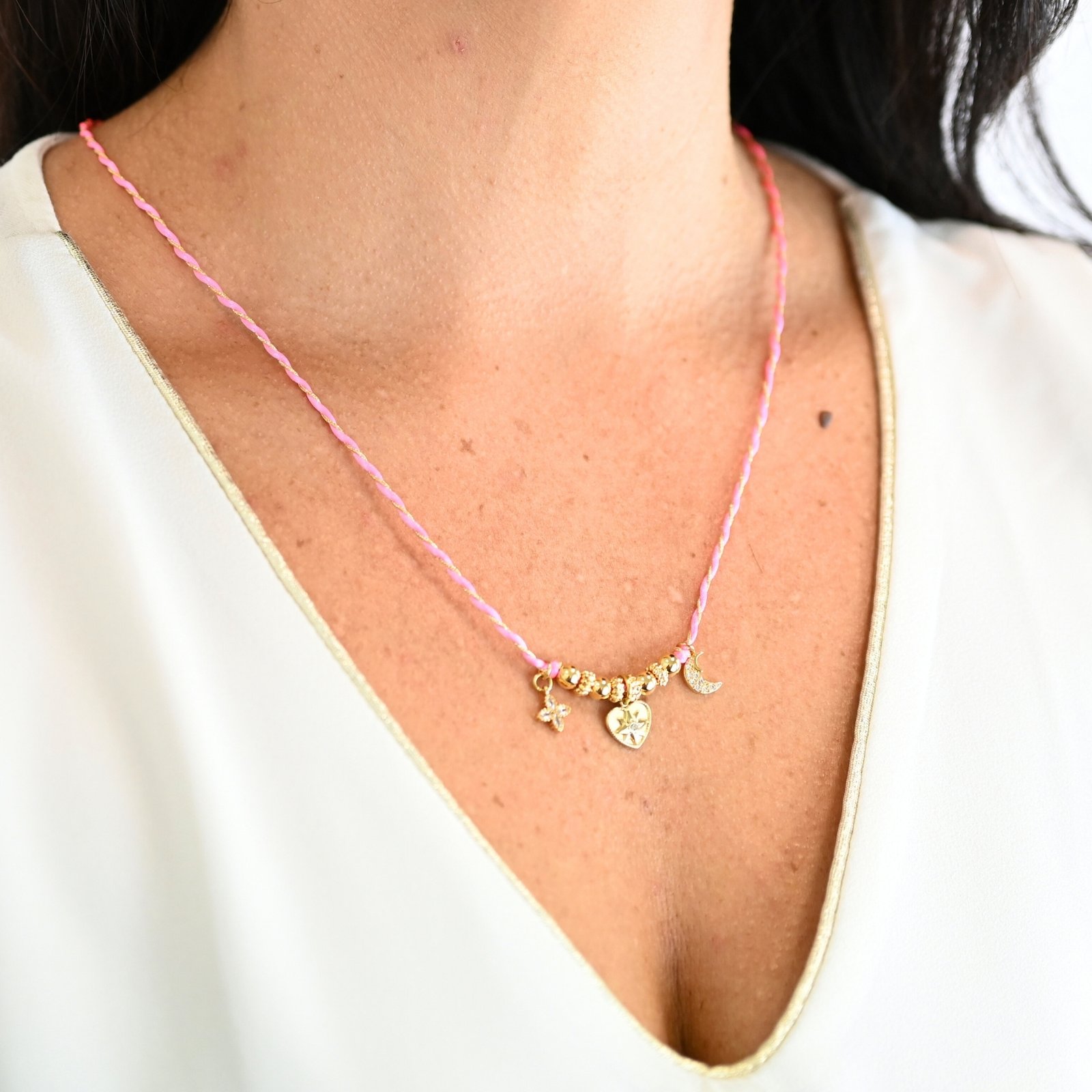 "Ces colliers mêlent fils de coton torsadé, touches dorées et couleurs vibrantes, pour une alliance parfaite entre raffinement et fraîcheur de l’océan. Ornés de trois charms et de détails en plaqué or, ils rappellent l’énergie chic des vagues et le charme intemporel des rivages de Biarritz. Une harmonie bohème et sophistiquée à porter au quotidien. Composition : Plaqué or et fils de coton torsadés. . Bijou porté, Crédit GEMITY."