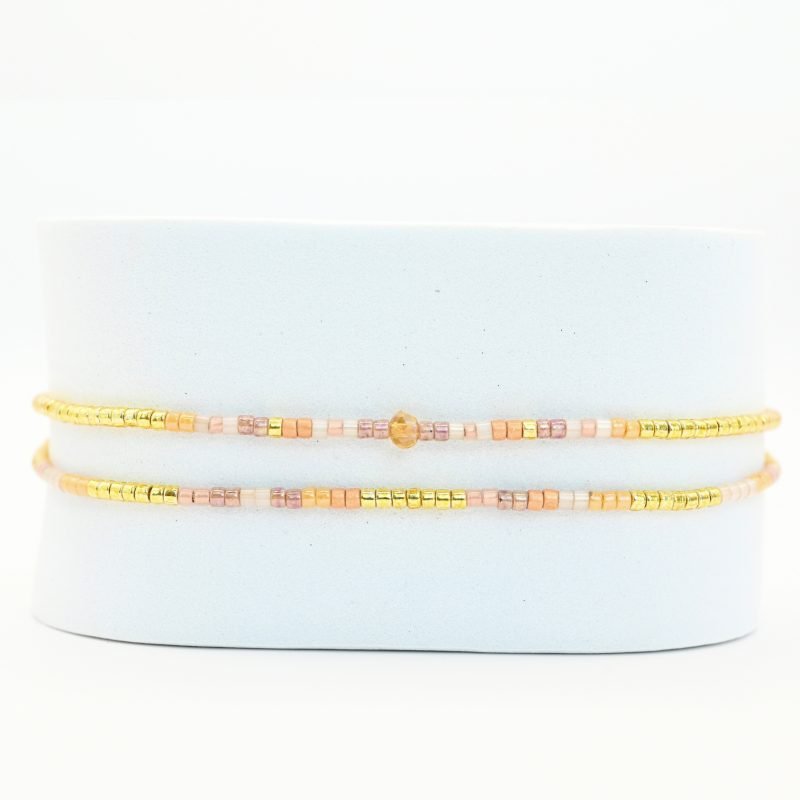 ce bracelet fin à 2 rangs associe des perles dorées, blanches, roses et nude pour un design doux et coloré. L'un des rangs est orné d’une perle plus grosse au centre, apportant une touche de sophistication à ce bijou délicat. . Bijou seul, Crédit GEMITY