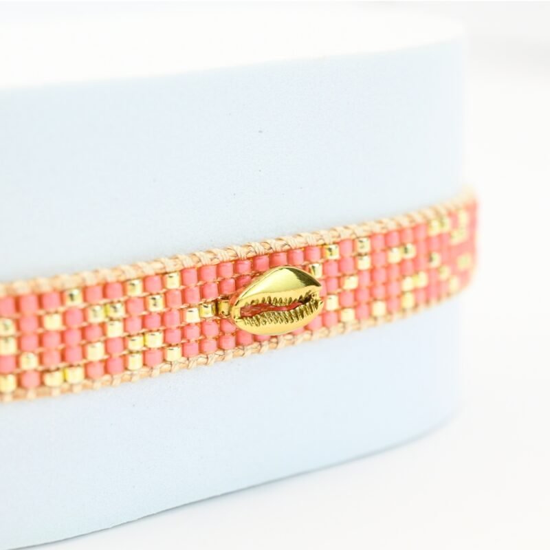 laissez-vous séduire par la beauté naturelle de cette petite manchette, composée de 5 rangs de perles corail soigneusement assemblées. L'ornement coquillage en son centre ajoute une touche marine et exotique, parfaite pour les amateurs de style bohème et élégant.. Bijou seul, Crédit GEMITY