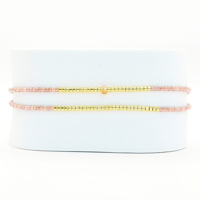 ce bracelet raffiné, composé de deux rangs, est l'accessoire parfait pour apporter de l'élégance à votre poignet. Le design associe des perles dorées et des perles nude, avec une disposition qui crée un équilibre parfait. . Bijou seul, Crédit GEMITY